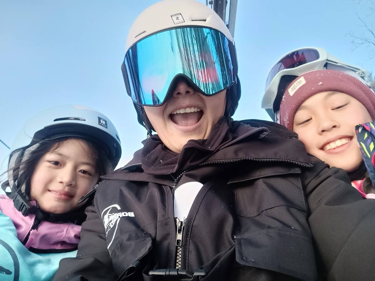 A coach and two young students smiling on a chairlift