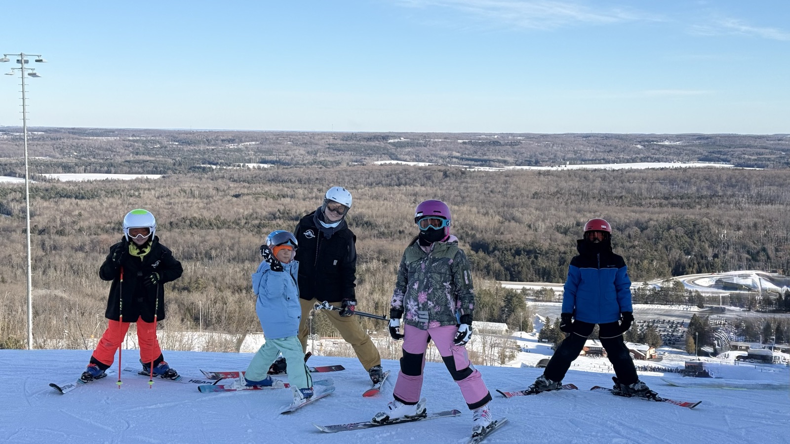 Kids and their coach at the top of the hill on a clear day